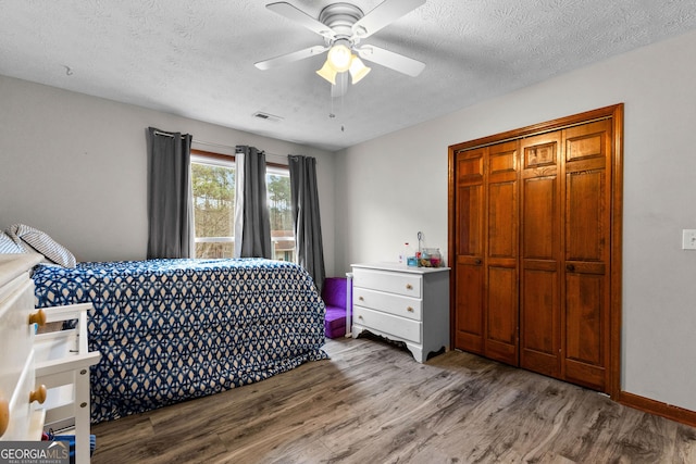 bedroom featuring ceiling fan, a closet, wood-type flooring, and a textured ceiling