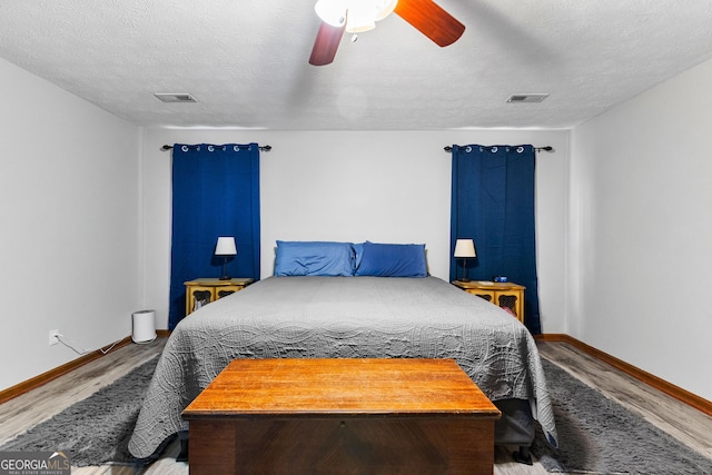 bedroom featuring ceiling fan, wood-type flooring, and a textured ceiling