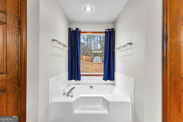 bathroom featuring a textured ceiling and a tub