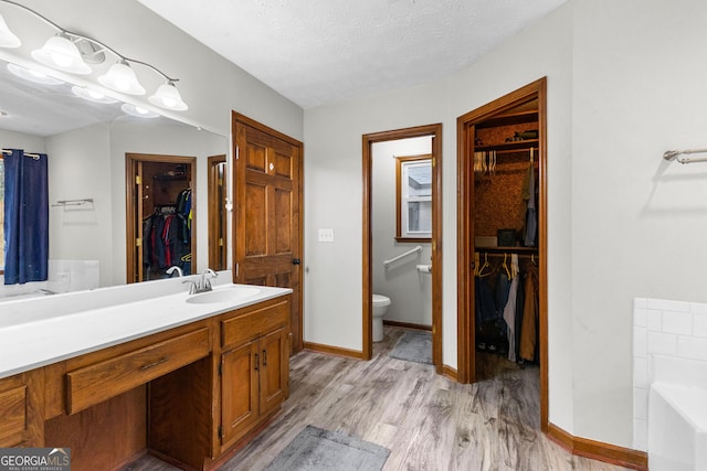 bathroom with hardwood / wood-style floors, vanity, a bathtub, toilet, and a textured ceiling