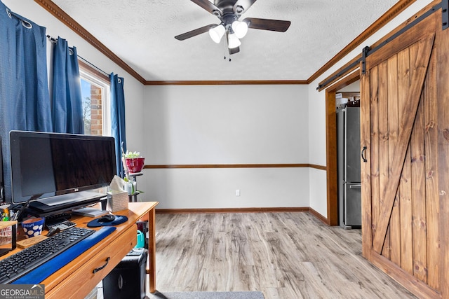 office with ornamental molding, a textured ceiling, ceiling fan, a barn door, and light hardwood / wood-style floors