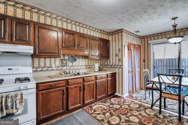 kitchen with a textured ceiling, decorative light fixtures, white gas range, and sink