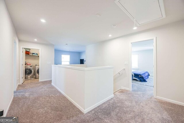 corridor with separate washer and dryer and light carpet