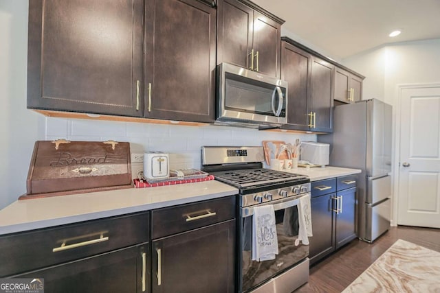 kitchen with stainless steel appliances, tasteful backsplash, dark brown cabinets, and dark hardwood / wood-style flooring