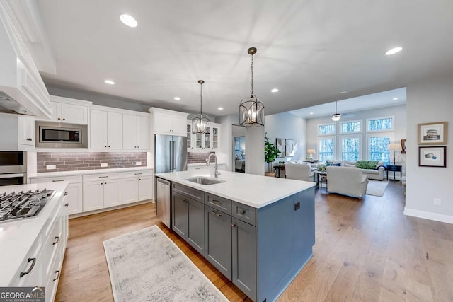 kitchen featuring light countertops, a sink, a kitchen island with sink, and white cabinetry