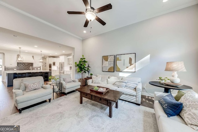 living area with recessed lighting, ceiling fan, light wood-style floors, and ornamental molding