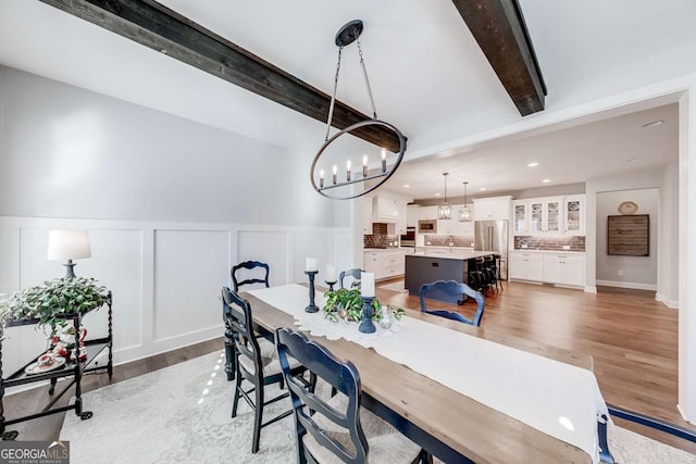 dining room with recessed lighting, a chandelier, beamed ceiling, and wood finished floors