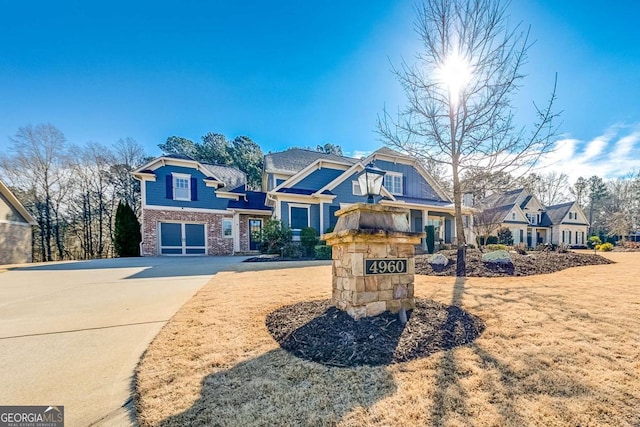 view of front facade featuring an attached garage, a residential view, concrete driveway, and a front yard