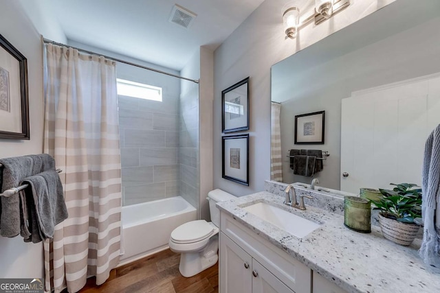 bathroom featuring shower / bath combination with curtain, visible vents, toilet, vanity, and wood finished floors