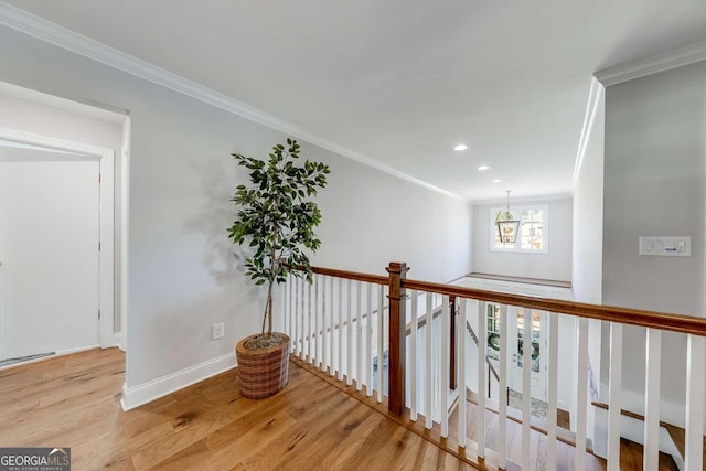 corridor featuring baseboards, ornamental molding, an upstairs landing, and light wood-style floors