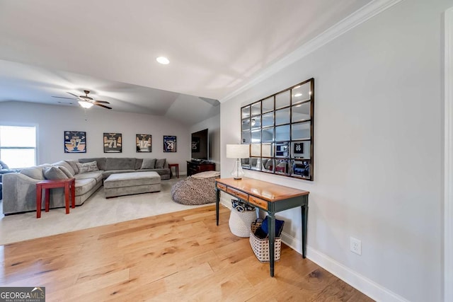 living room with ornamental molding, ceiling fan, vaulted ceiling, wood finished floors, and baseboards