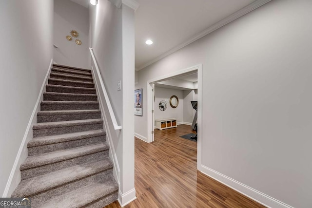 staircase with recessed lighting, baseboards, wood finished floors, and ornamental molding