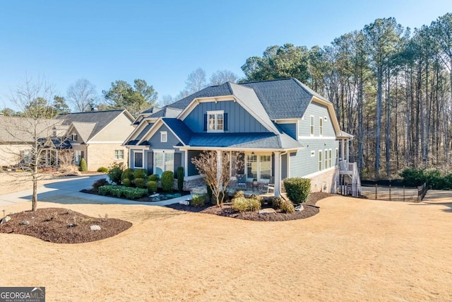 view of front of home with board and batten siding, driveway, a shingled roof, and fence