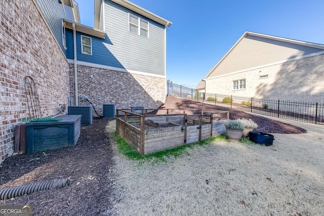 view of home's exterior with central air condition unit, a garden, brick siding, and fence