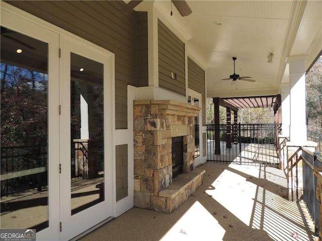 view of patio / terrace featuring a ceiling fan, an outdoor stone fireplace, and french doors