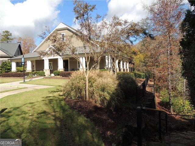 view of front of property with stairs, a front lawn, and stucco siding