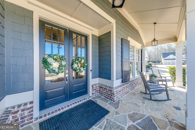 entrance to property with covered porch, french doors, and brick siding