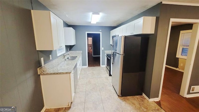 kitchen featuring white cabinets, sink, light tile patterned floors, appliances with stainless steel finishes, and light stone counters