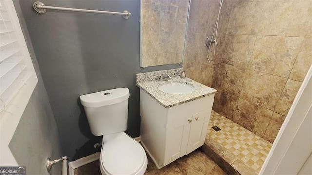 bathroom featuring a tile shower, vanity, and toilet