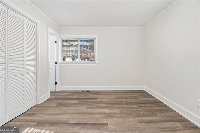 unfurnished bedroom with a closet, wood-type flooring, and ornamental molding