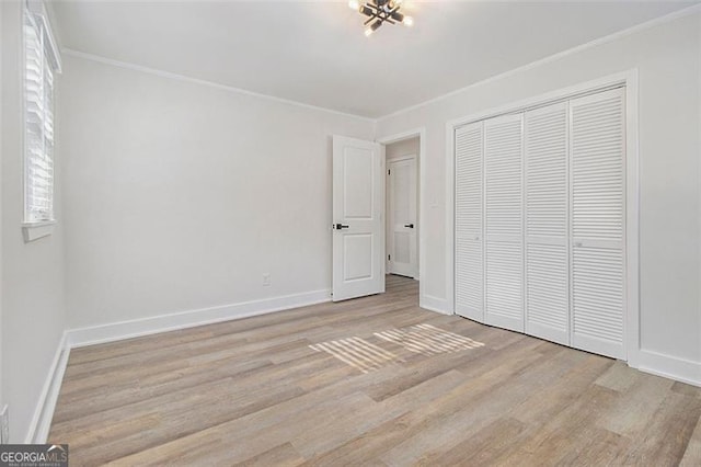 unfurnished bedroom featuring light hardwood / wood-style flooring, a closet, and crown molding