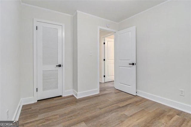 empty room with crown molding and light hardwood / wood-style flooring