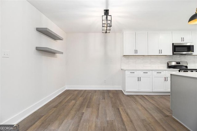 kitchen with white cabinets, appliances with stainless steel finishes, tasteful backsplash, and dark wood-type flooring