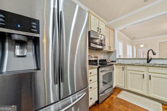 kitchen featuring cream cabinets, sink, dark hardwood / wood-style floors, light stone counters, and stainless steel appliances