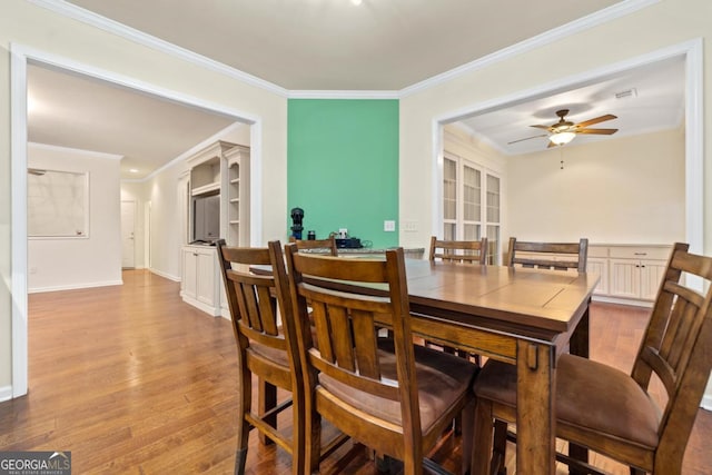 dining area featuring ceiling fan, light wood-type flooring, and ornamental molding