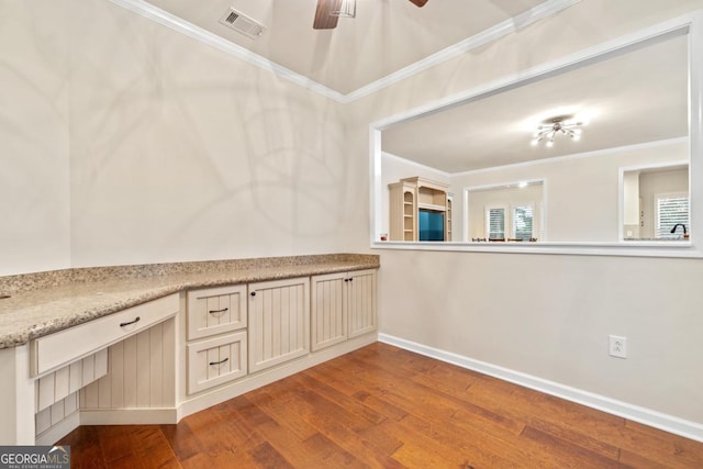 kitchen with hardwood / wood-style flooring, ceiling fan, ornamental molding, and cream cabinetry