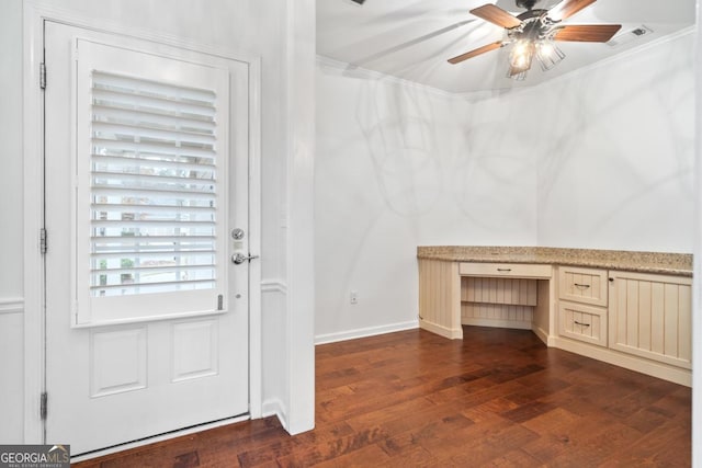 doorway featuring dark hardwood / wood-style flooring, built in desk, ceiling fan, and ornamental molding