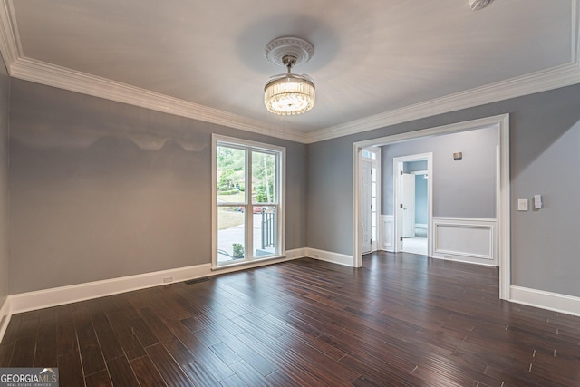 spare room featuring dark hardwood / wood-style floors, an inviting chandelier, and crown molding