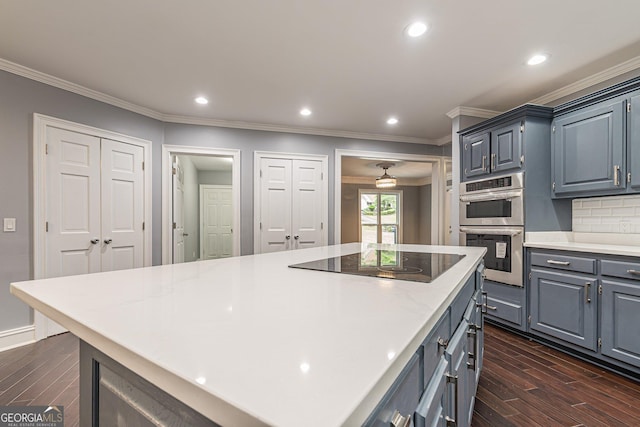 kitchen with black electric stovetop, backsplash, double oven, dark hardwood / wood-style floors, and a kitchen island