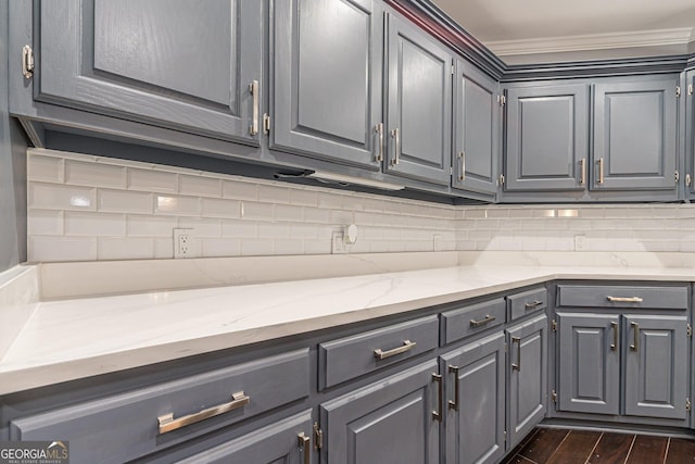 kitchen with gray cabinets, light stone counters, and backsplash