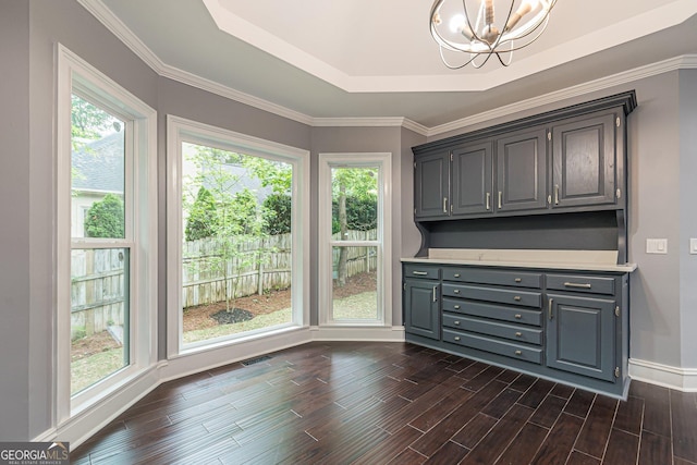 unfurnished dining area featuring an inviting chandelier, a raised ceiling, plenty of natural light, and crown molding