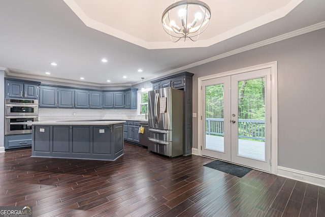 kitchen featuring a center island, stainless steel appliances, an inviting chandelier, pendant lighting, and a tray ceiling