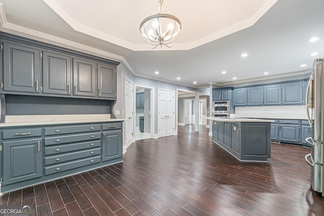 kitchen with gray cabinetry, a center island, a raised ceiling, pendant lighting, and appliances with stainless steel finishes