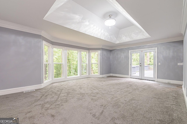 carpeted empty room with a raised ceiling, crown molding, and french doors