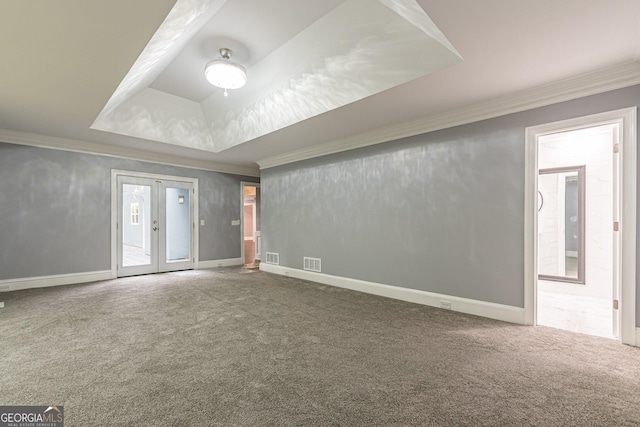 carpeted spare room with a tray ceiling, crown molding, and french doors