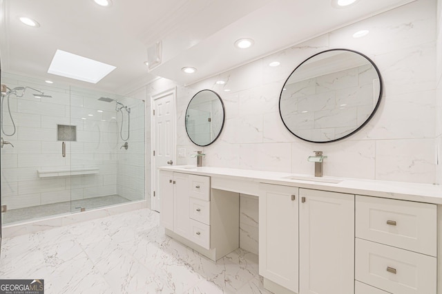 bathroom featuring a skylight, a shower with door, vanity, tile walls, and ornamental molding