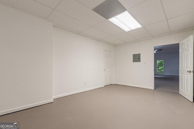 empty room with concrete flooring, electric panel, and a drop ceiling