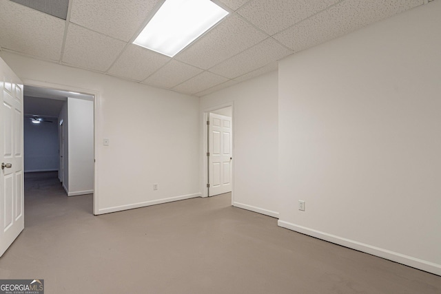 spare room with a paneled ceiling and concrete floors