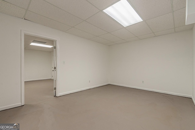 spare room with a paneled ceiling and concrete flooring