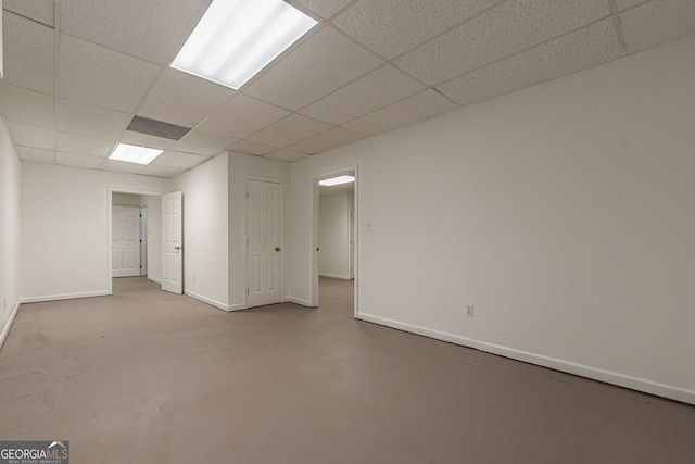 spare room with a paneled ceiling and concrete flooring