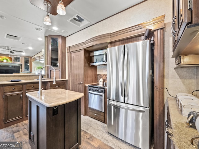 kitchen featuring decorative light fixtures, an island with sink, appliances with stainless steel finishes, and dark wood-type flooring