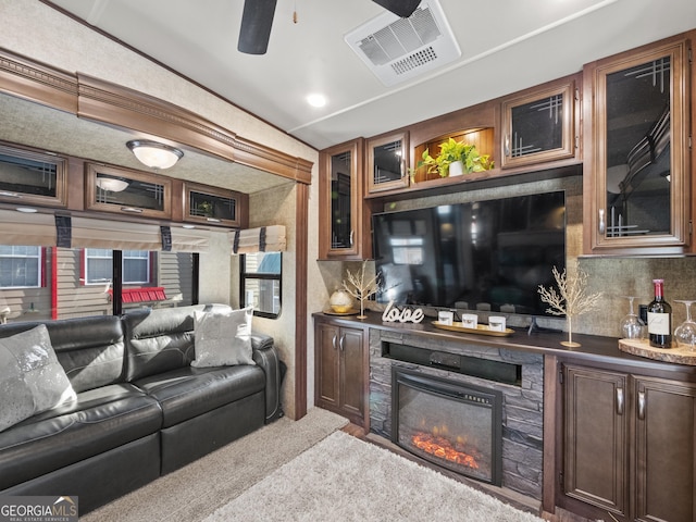 bar featuring light carpet, decorative backsplash, a stone fireplace, and ceiling fan