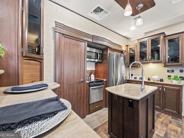 kitchen with a center island, dark hardwood / wood-style floors, pendant lighting, dark brown cabinets, and appliances with stainless steel finishes