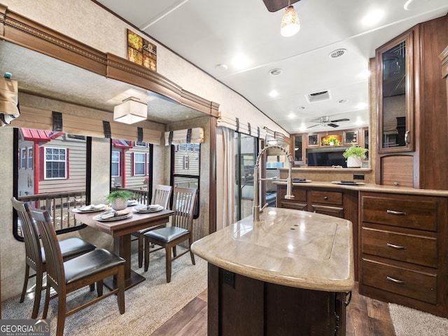 kitchen with ceiling fan, a center island, dark wood-type flooring, and vaulted ceiling