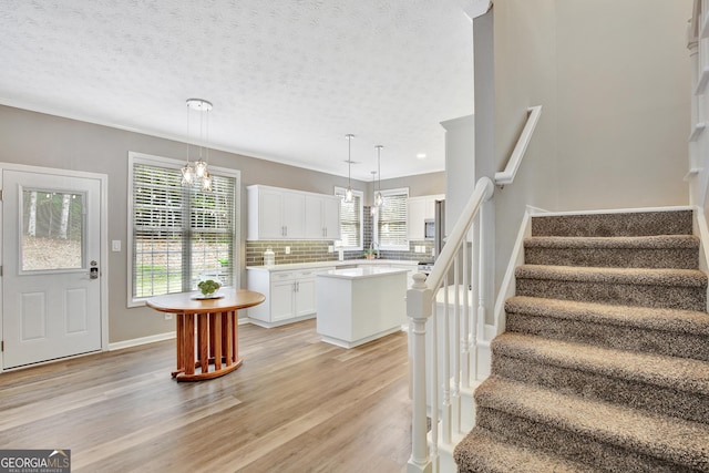 kitchen featuring white cabinetry, a kitchen island, a healthy amount of sunlight, and decorative light fixtures