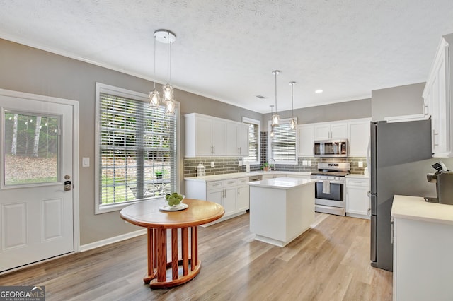 kitchen featuring white cabinets, pendant lighting, a kitchen island, and stainless steel appliances